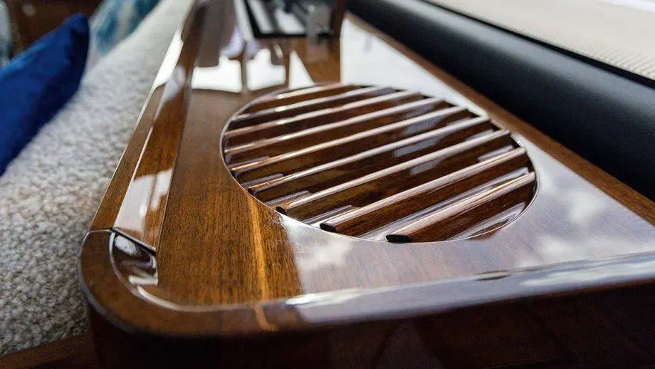 Close-up of a polished wooden surface with a circular vent, featuring slotted grill design, in a luxury interior setting.